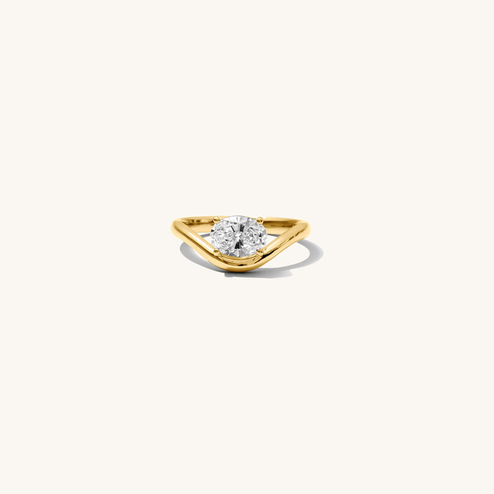 Close up of the gold Solitaire Wave pinky ring with an oval stone on a white background
