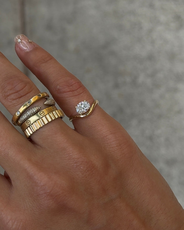 Gold Solitaire Wave pinky ring with an oval solitaire stone in a wave-shaped setting