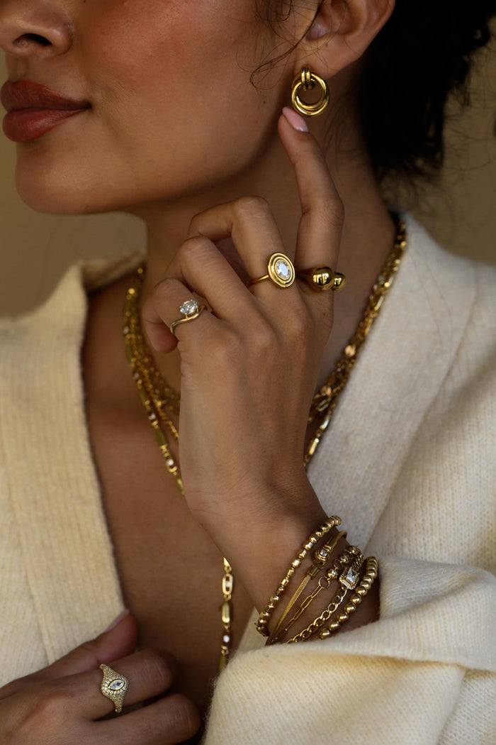 Gold Solitaire Wave pinky ring, a slim band curving up to a single oval stone