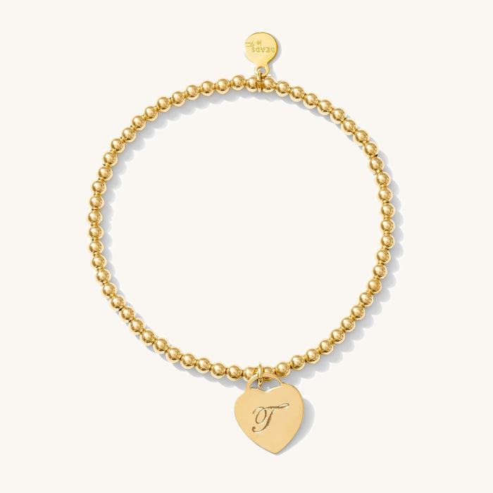 Close up of a gold bracelet with charm on a white background