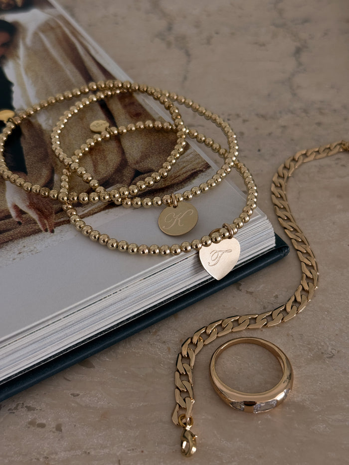 Assorted gold jewelry on a stone table with a coffee table book