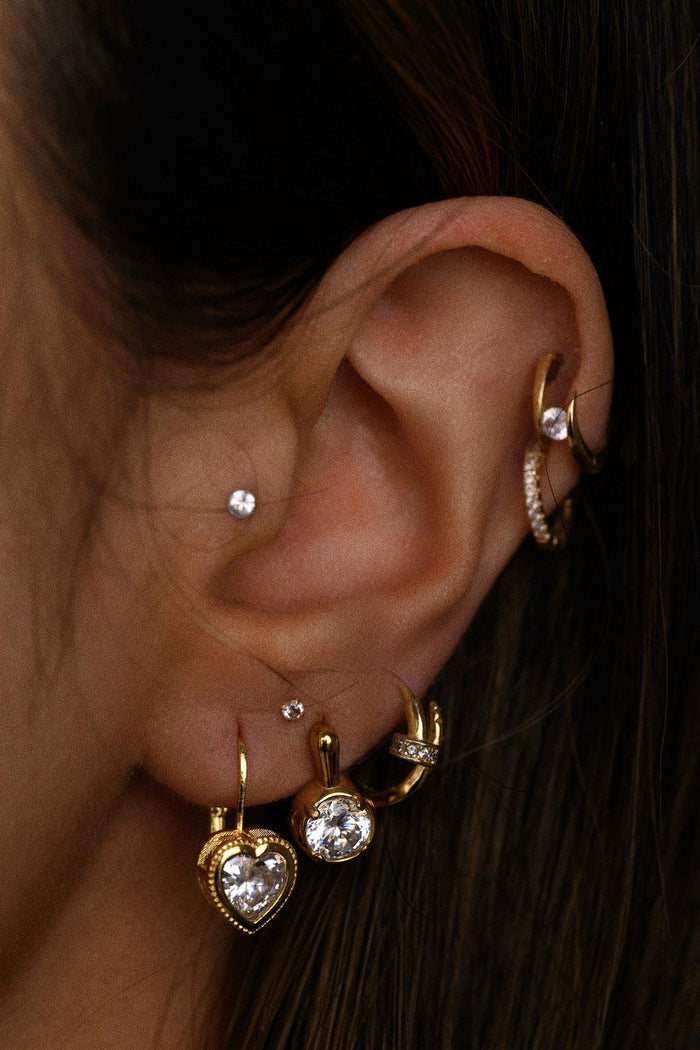 Close-up of an ear with multiple gold and diamond earrings.