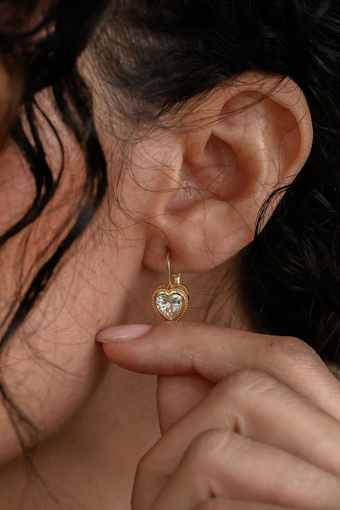 Close-up of a woman wearing a gold earring with a heart design.