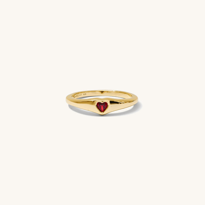 Gold ring with a red heart on a white background