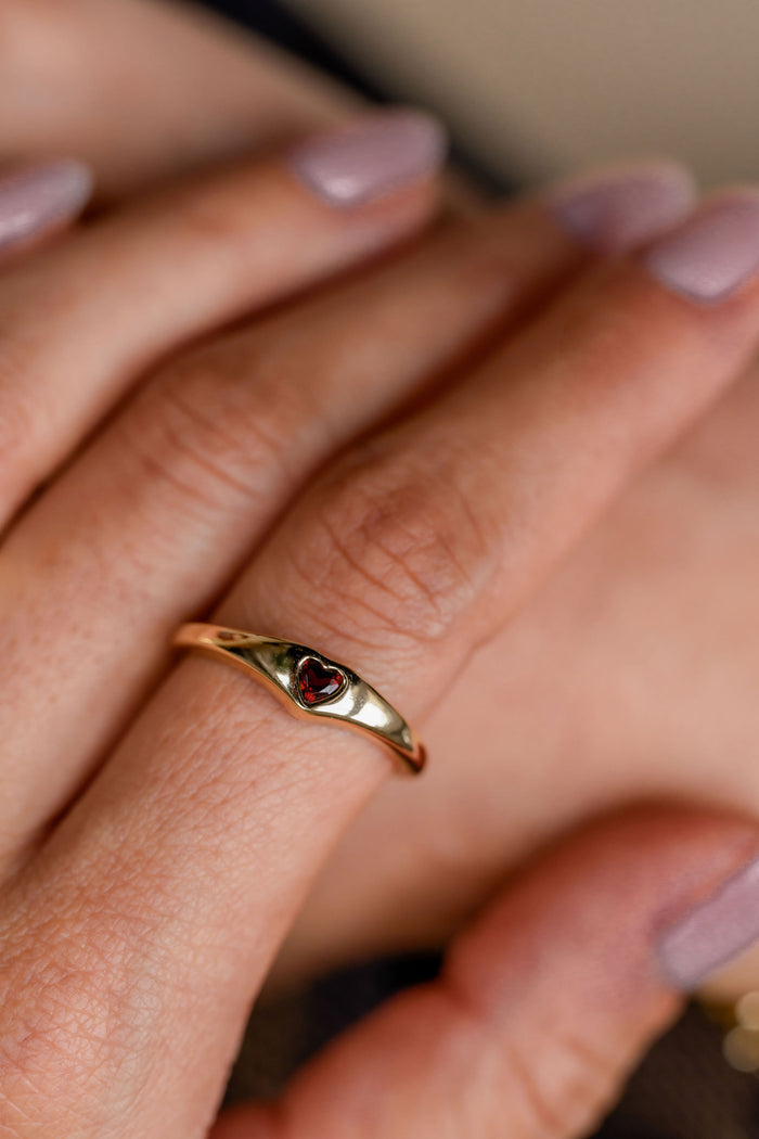 Gold ring with a red gemstone on a person's finger