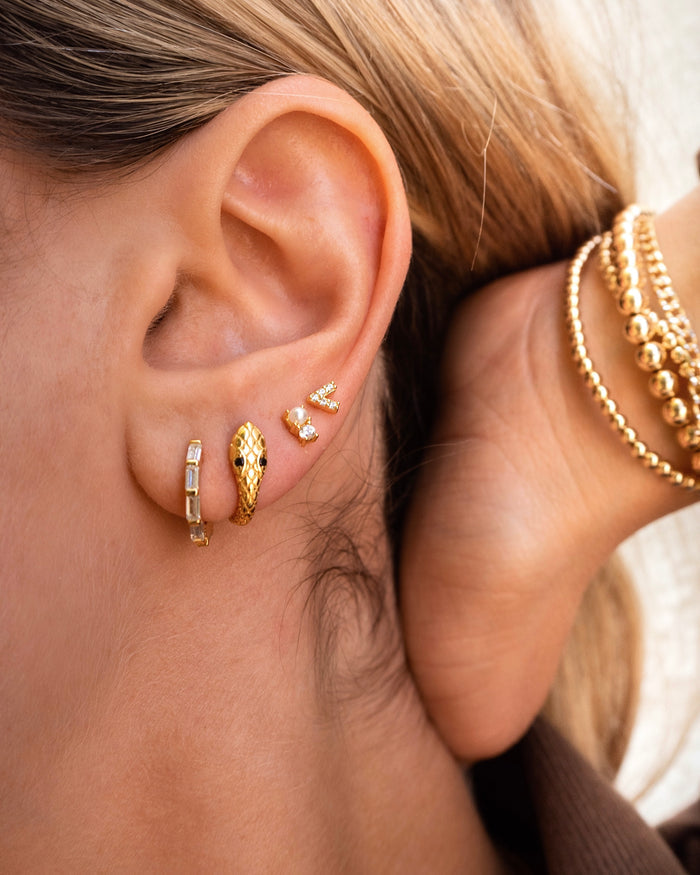 Close-up of an ear with multiple gold huggies and studs
