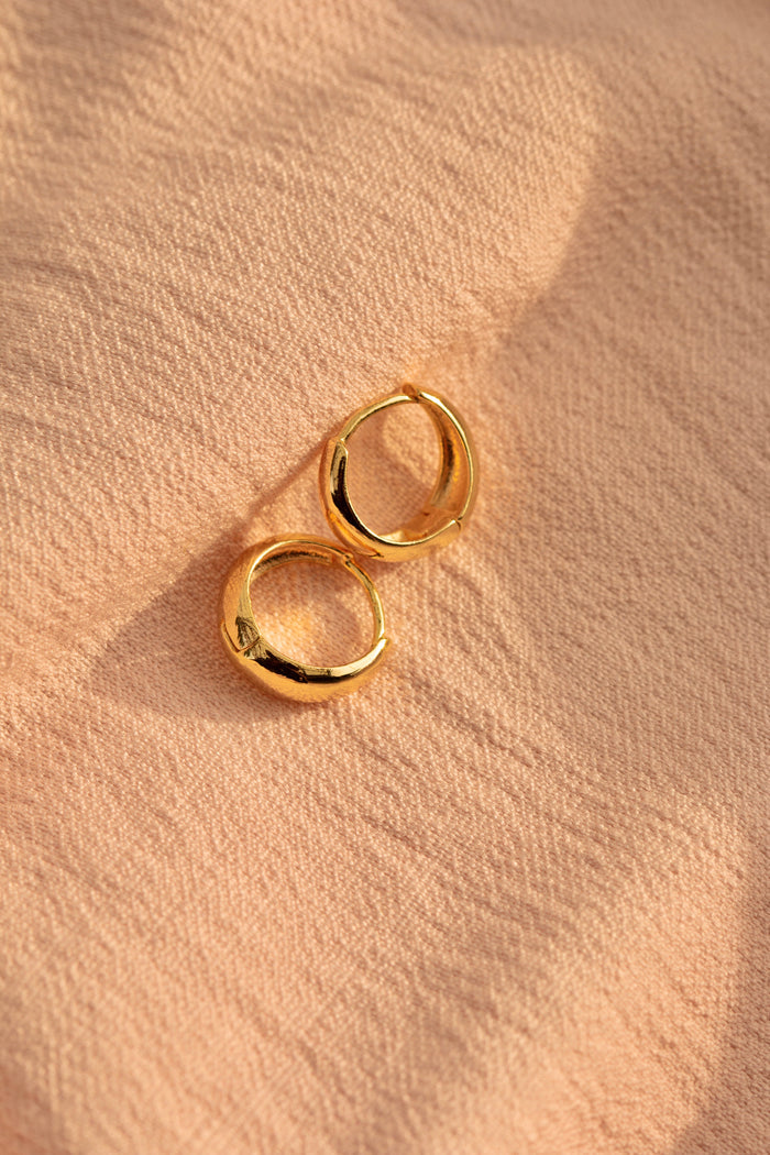 Close up of gold hoops on a neutral textured cloth