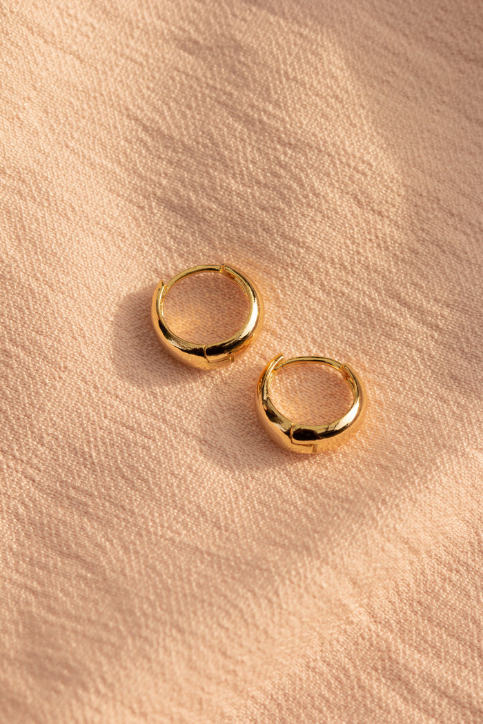 Close up of gold hoops on a neutral textured cloth