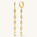 close up of gold stone dangle earrings on a white background