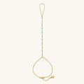 Close up of gold hand chain with teal bead accents on a white background