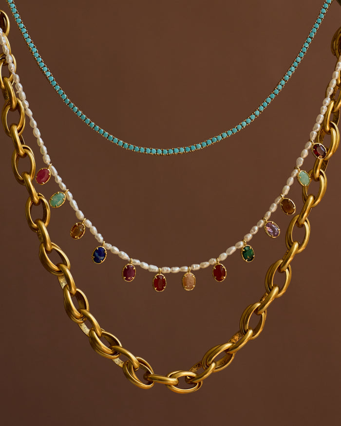 Three necklaces with different designs on a brown background