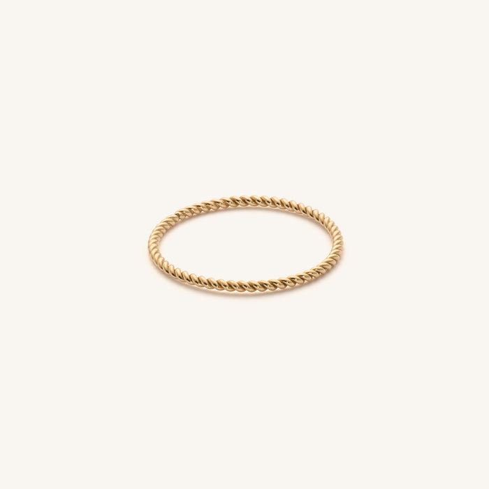 Close up of a hand wearing the gold Twist rope ring stacked with slim bands