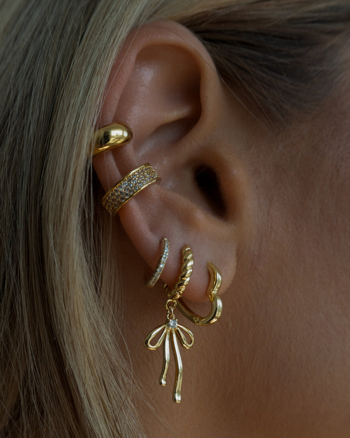 Close-up of an ear with multiple gold and crystal earrings