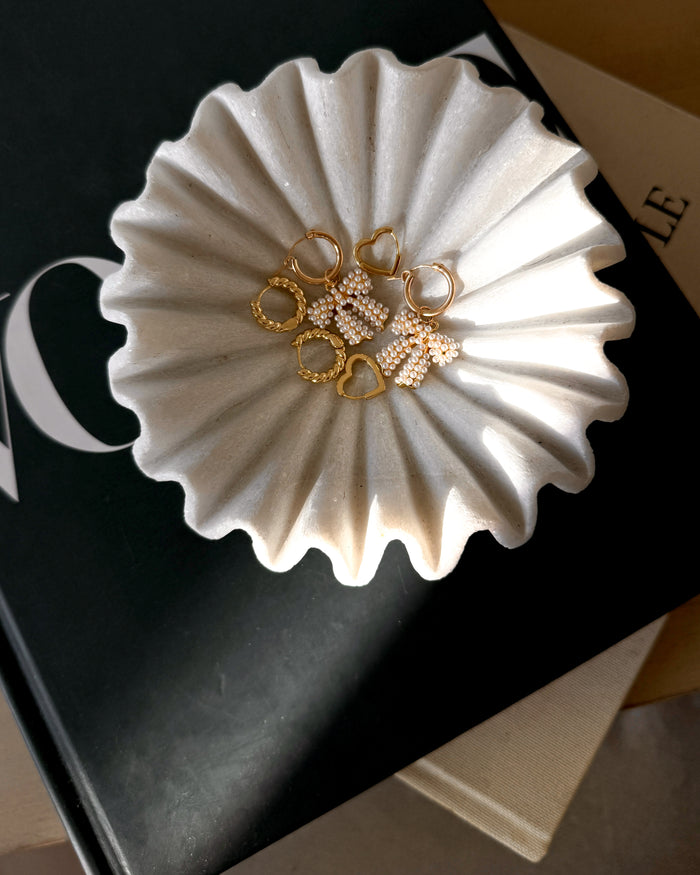 Gold hoop earrings in a textured white dish