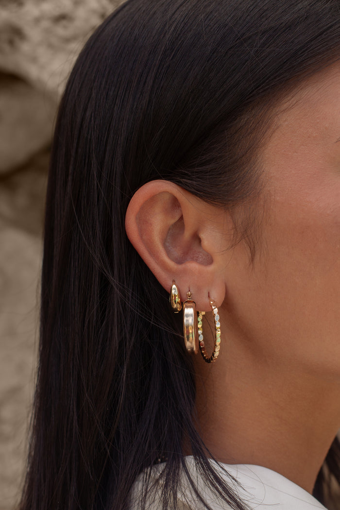 Close-up of an ear with multiple gold earrings