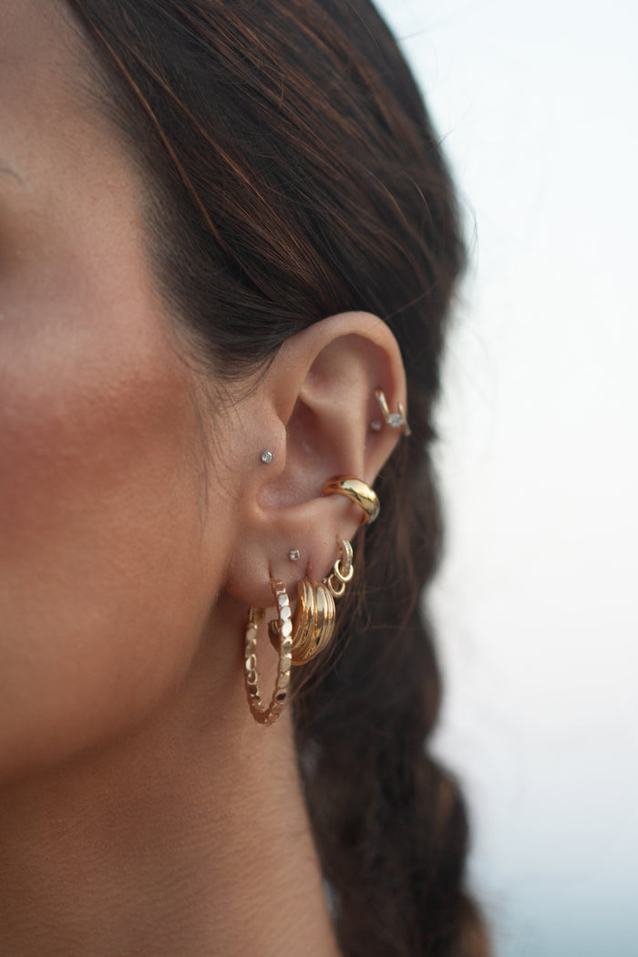Close-up of an ear with multiple gold earrings