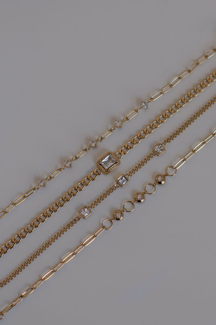 Gold chain bracelets with stone accents on a white background