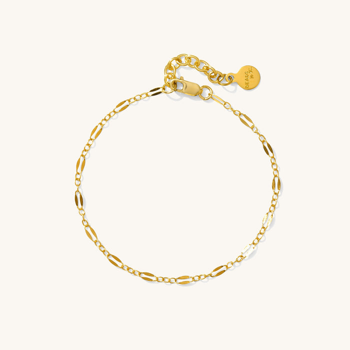 Close up of a delicate gold chain bracelet on a white background