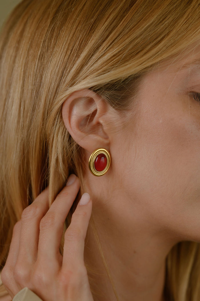 Close up of a woman wearing red and gold accent earrings