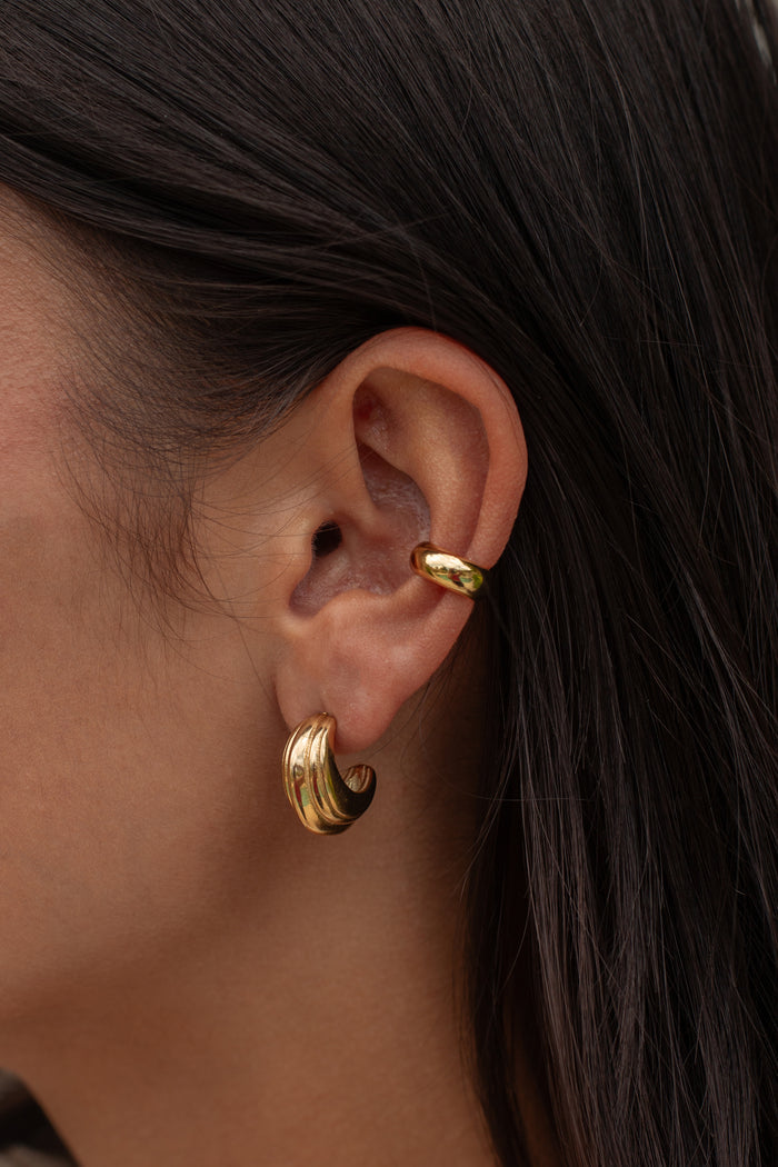 Close-up of an ear with multiple gold earrings