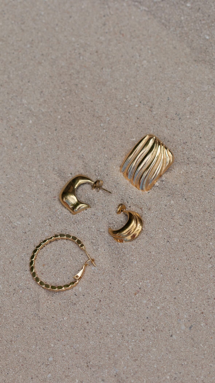Gold earrings on a stone background