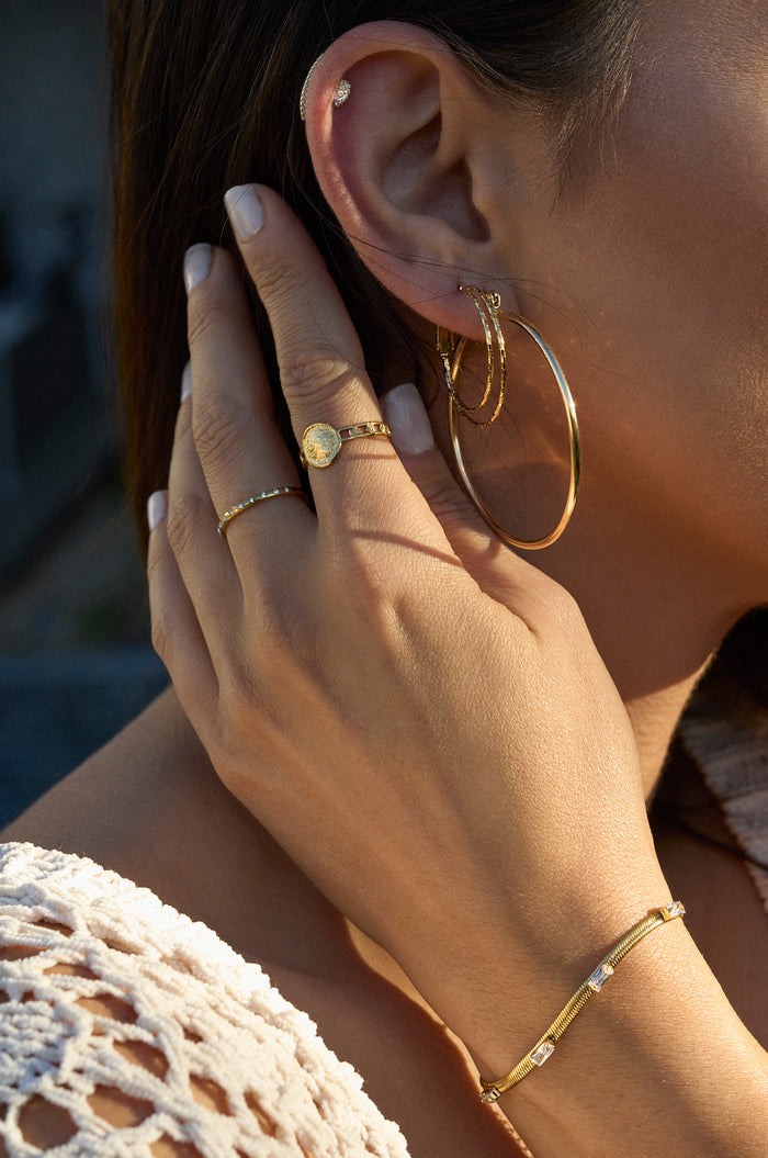 A woman wearing gold earrings and rings
