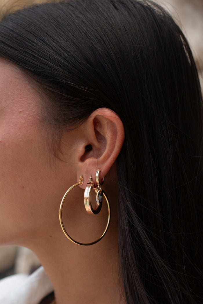 Close-up of an ear with multiple gold hoops of different sizes