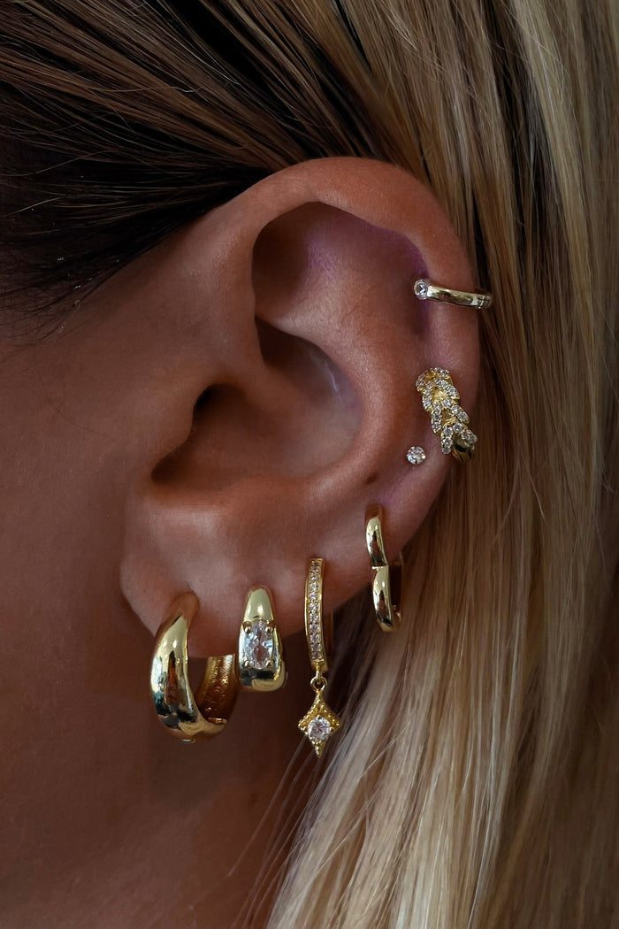 Close-up of an ear with multiple gold earrings
