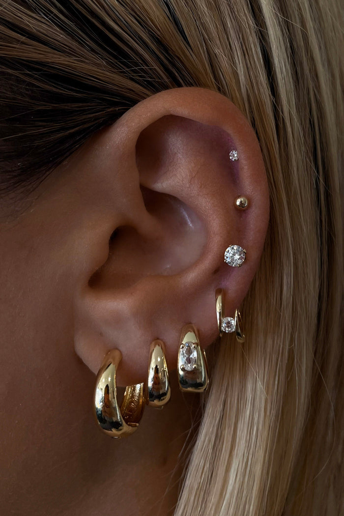 Close-up of an ear with gold earrings and hair details