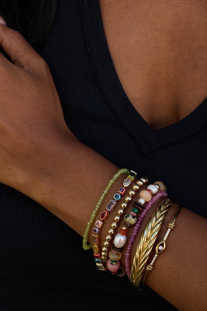 Close-up of a person's arm wearing multiple colorful bracelets on a black background