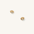 Close up of eye-shaped gold stud earrings on a white background