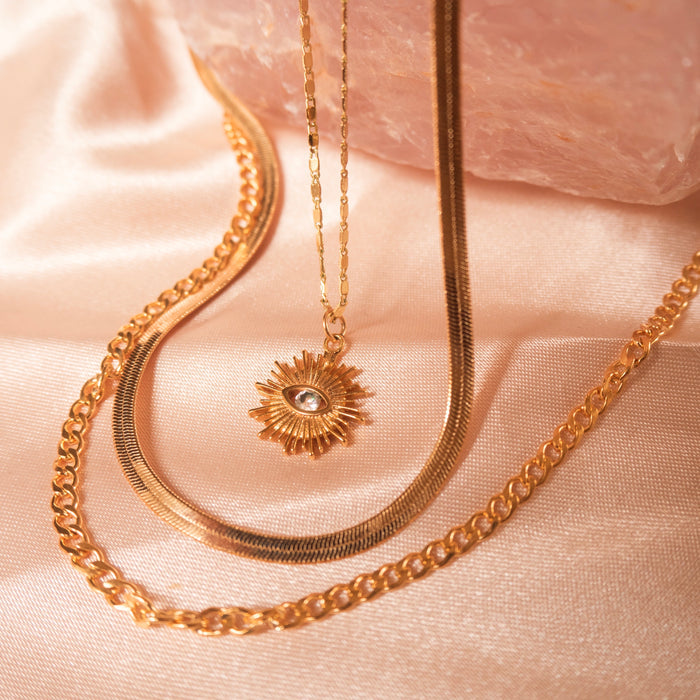 The Yaz evil eye necklace worn layered with dainty gold chains